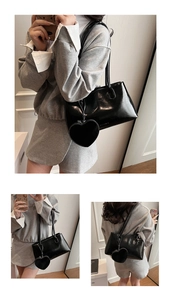 Detail of black patent leather shoulder bag with vintage heart pendant and dual straps