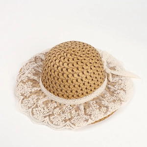 Detail of woven straw sun hat featuring elegant white lace trim and a large floral bow