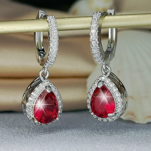 Macro shot of silver drop earrings with pear-cut red stone and sparkling zircon halo