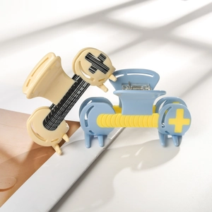 Y2K style acetate hair claw clips with contrast stripe and cross motif on white surface