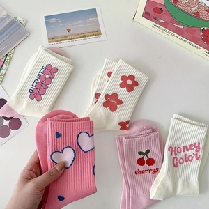 Detailed view of pink and white cotton crew socks with heart, flower and cherry patterns