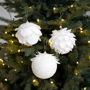 Close-up of white petal foam Christmas balls with glitter hanging on a decorated tree