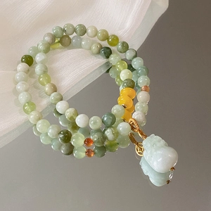 Makro-Detail von chinesischem Jade-Perlenarmband mit Pixiu-Anhänger auf Seide