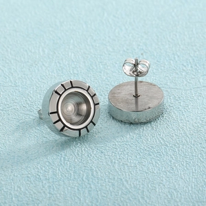 Gros plan de boucles d'oreilles en acier argenté avec bords texturés et design rond