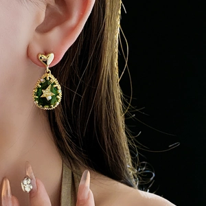 Detail of gold-plated waterdrop earring with green pear-shaped stone and star pearl