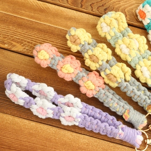 Handmade woven daisy keychains in pastel colors on a rustic wooden background