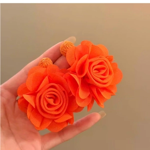 Detailed macro view of bright orange chiffon flower earrings with multilayered fabric petals