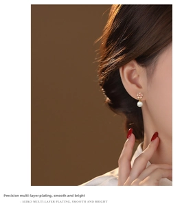 Detail view of pink cherry blossom enamel earrings with white pearls on a model