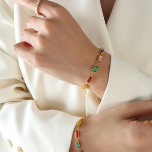 Luxurious gold bracelet set with colorful rectangular zircons worn with matching ring