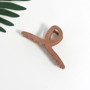 Macro shot of large tan velvet flocked hair claw clip with twisted texture and grip teeth