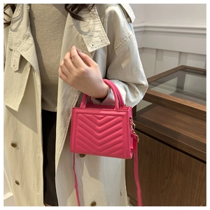 Pink quilted PU leather crossbody bag with chevron texture worn by a model in a trench coat