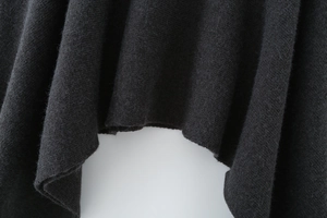 Detailed close-up of dark grey asymmetric hem showing high-density knit fabric texture