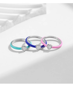 Macro shot of silver rings with blue and pink enamel coating and heart-shaped gemstone details