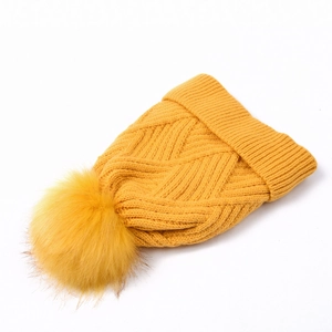 Bright yellow winter knit beanie featuring a large faux fur pompom and thick cable texture
