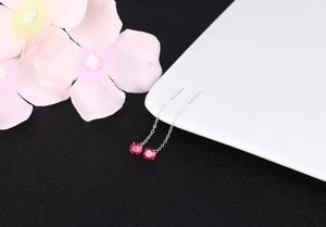 Detail of red cubic zirconia tassel earrings with elegant long silver chain on ceramic