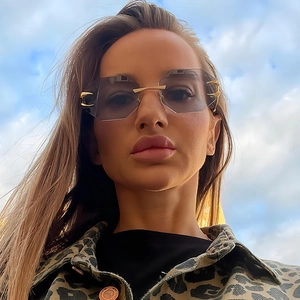 Rimless geometric sunglasses with purple lenses and gold accents against blue sky