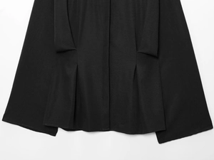 Macro detail of black structured pleated fabric showing woven texture and sewing quality