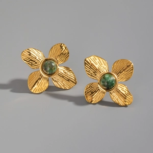 Détail de boucles d'oreilles fleurs dorées avec pierres vertes et pétales texturés