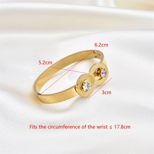 Detailed size measurement of a gold oval bangle with zircons on white silk background