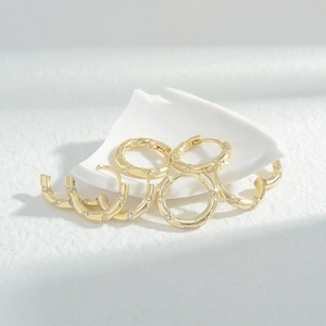 Detail of gold-plated twisted hoop earrings with sparkling white zircon inlays