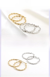 Detail of twisted rope hoop earrings in high-polished gold and silver finish
