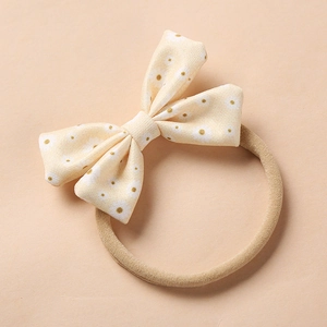 Detail of baby bow headband with yellow daisy floral print and soft elastic nylon band