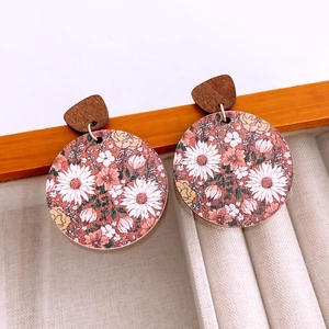 Macro shot of large round wooden earrings with floral patterns and a brown stud