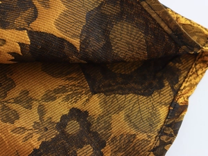 Detailopname van goud-zwarte jacquardstof met geweven textuur en metallic glans details