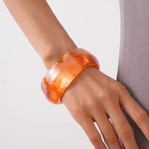 Close-up of a wide acrylic resin bangle with amber texture and marble finish