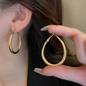 Detailed view of polished gold teardrop earrings showing thick hoop design and texture