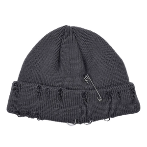 Grey distressed knit beanie with silver safety pin and metal rings in punk style