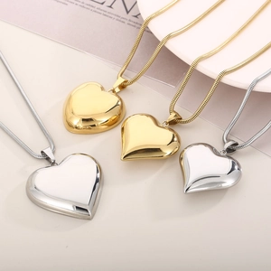 Detail of large and small hollow heart pendants in gold and silver on snake chains