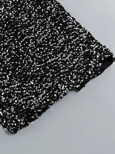 Détail de paillettes argentées haute densité sur une robe de soirée noire scintillante