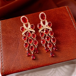 Macro detail of vintage gold earrings with red drop gemstones and white zircon accents