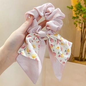 Detailed shot of pink floral bow scrunchie made of soft satin fabric for hair styling