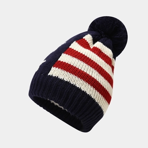 Detail of winter knitted hat with US flag pattern and fluffy dark blue pom-pom top