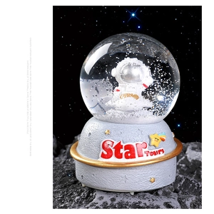 Detail of astronaut crystal ball music box with resin base and starry space theme