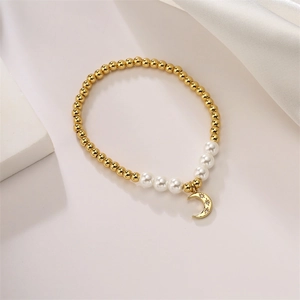 Detail of beaded gold bracelet with white pearls and a crescent moon star pendant