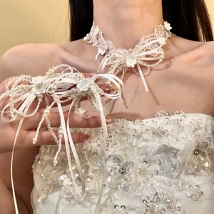 Close-up detail of white lace choker with pearls and floral bows on bridal gown