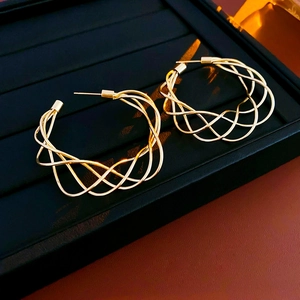 Macro shot of gold woven mesh hoop earrings on black velvet jewelry display