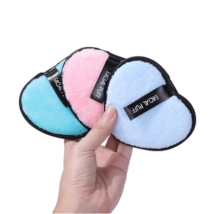 Three heart-shaped microfiber facial puffs in pink and light blue with black finger straps