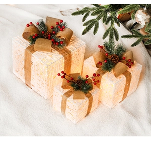 Macro detail of lighted Christmas gift boxes with pine cones and festive burlap bows