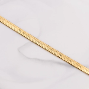 Polished 18k gold plated 4mm flat snake chain bracelet for women on marble background