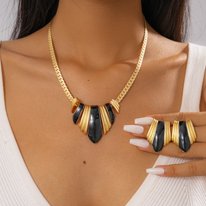 Detailed view of vintage gold necklace and earring set with black enamel fan design