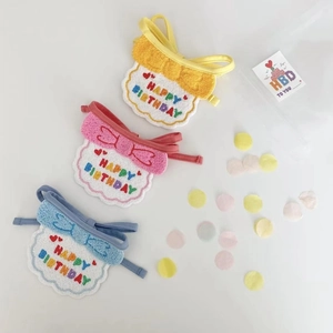 Close-up of three macaron-colored dog birthday bibs with happy birthday embroidery