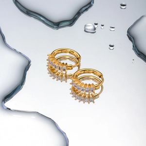 Boucles d'oreilles créoles françaises en acier doré 18k avec zircons sur surface d'eau