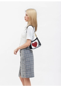 Detail of transparent PVC crossbody bag with red heart logo and elegant gold chain strap
