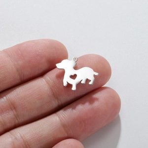 Detail of a small stainless steel puppy charm with heart cutout held by fingers