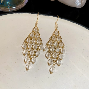 Macro shot of gold tassel earrings with clear faceted crystal beads on a ceramic tray