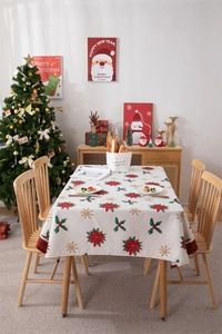 Detail of Christmas tablecloth featuring red poinsettia, gold snowflakes and plaid edges